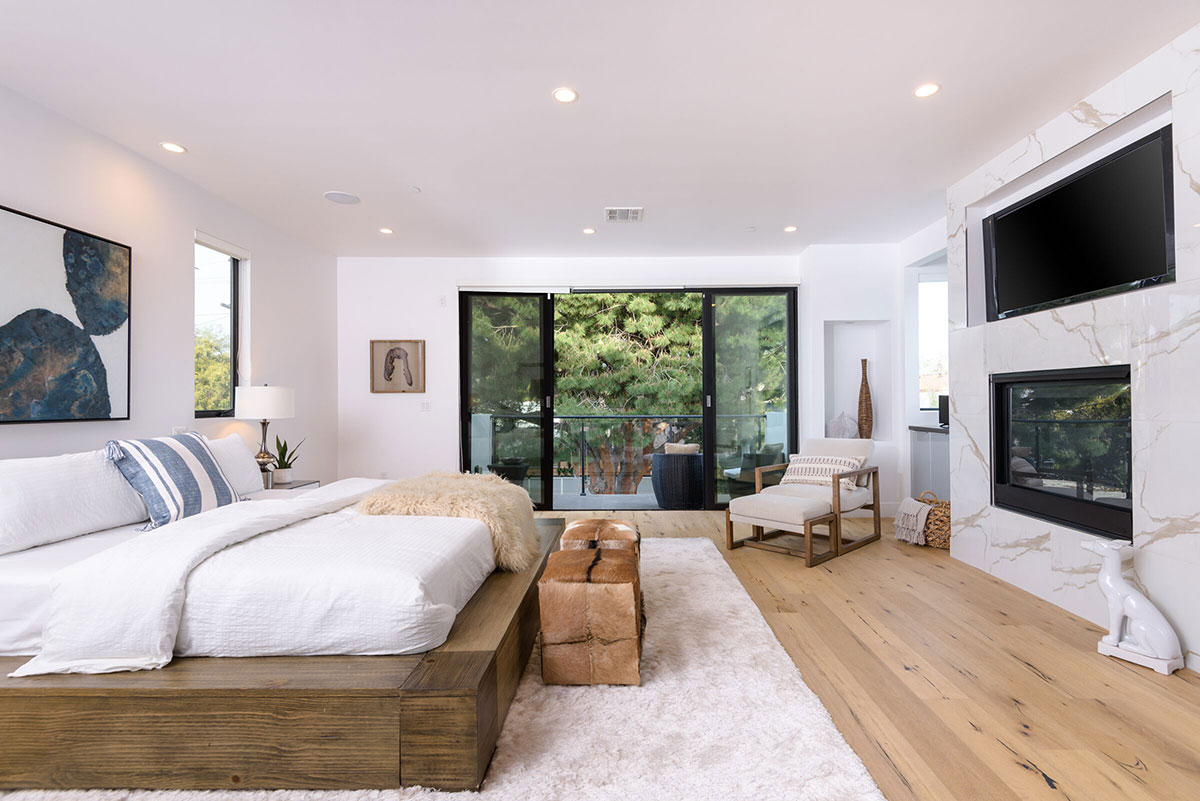 Bedroom with rustic wood bed frame, fireplace and TV.