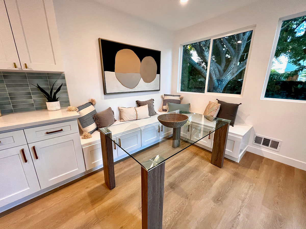 Corner of staged room with wood-legged glass table and white cabinetry.